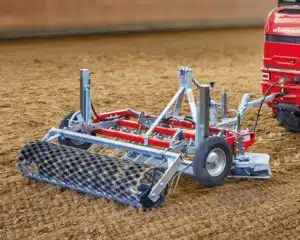 Herse agricole attelée à un tracteur rouge