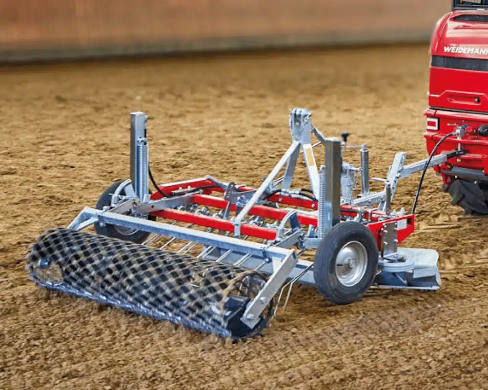 Herse agricole attelée à un tracteur rouge